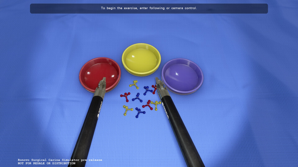 Pick-and-place exercise: two instruments above red, yellow and purple dishes and small jacks on a blue drape
