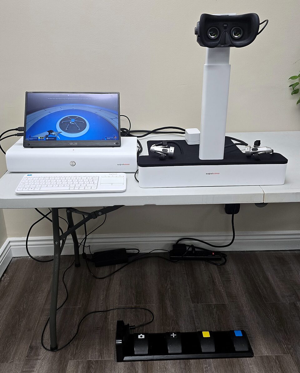 Robotix Express simulator on a table, with stereo viewer, hand controllers, monitor and foot pedals
